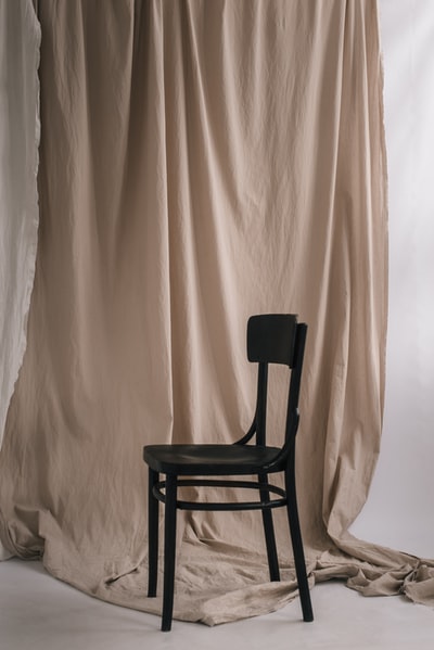白色窗帘旁的黑色木椅